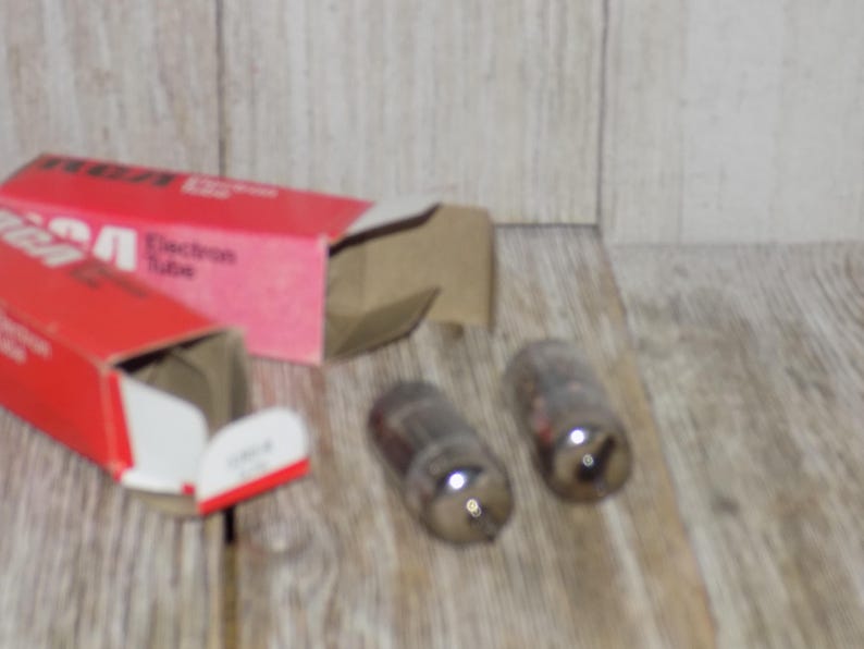 May include: Two vintage RCA Electron Tube vacuum tubes with a red and white box. The box is open, revealing the tubes and the text "Electron Tube". The tubes are glass with a dark interior.