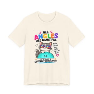 May include: A cream-coloured t-shirt featuring a graphic of a cat wearing rainbow sunglasses and holding a blue protractor. The text reads: ALL ANGLES ARE BEAUTIFUL, Acute, Obtuse, Right, Reflex, You're all Right!, IT'S JUST A DIFFERENT PERSPECTIVE.