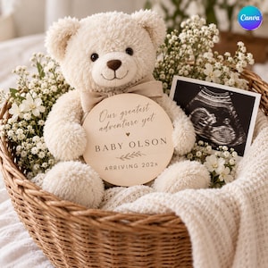 Puede incluir: Un oso de peluche color crema con una pajarita beige sentado en una cesta de mimbre llena de flores blancas de paniculata. El oso sostiene un disco de madera con el texto: Our greatest adventure yet, BABY OLSON, ARRIVING 202x. Se ve una ecografía.