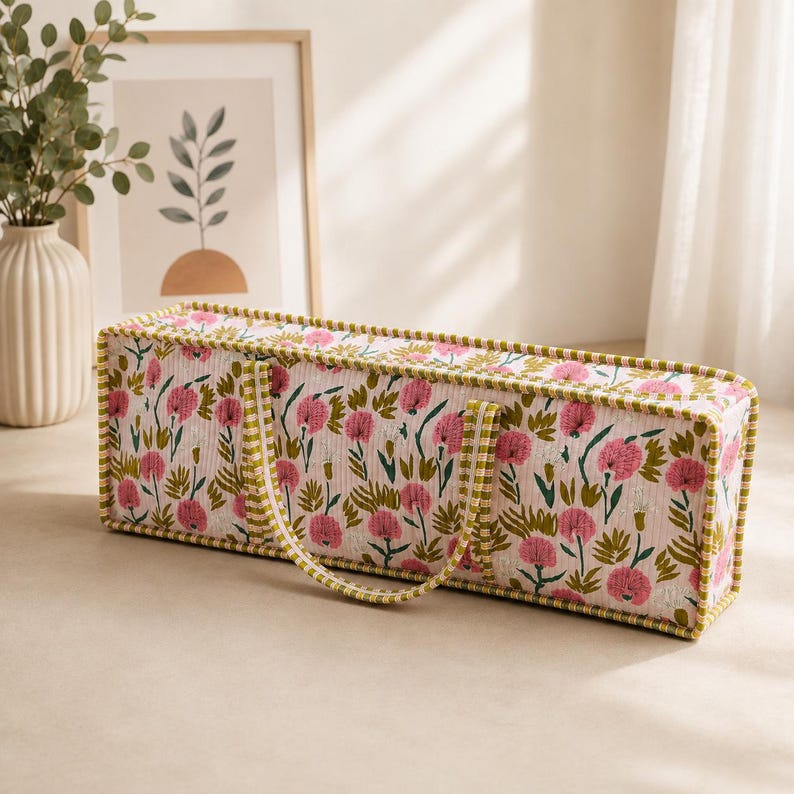 May include: A rectangular quilted storage bag featuring a repeating pattern of pink flowers and green foliage on a white background. The bag has a structured shape with green and white striped fabric trim along the edges and two matching fabric handles.