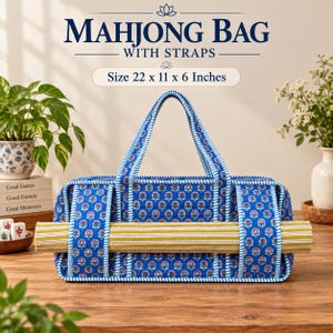 May include: A quilted blue mahjong bag with a pink and green floral pattern, featuring blue and white striped straps and trim. The bag measures 22 x 11 x 6 inches and holds a long, yellow and white striped mat across its front exterior.