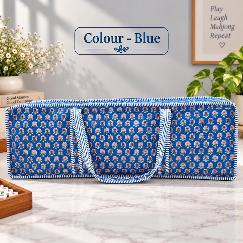 May include: A rectangular blue fabric storage bag featuring a repeating pattern of small pink flowers with green leaves. The bag has two matching blue and white striped fabric handles and matching striped piping along all the outer edges.