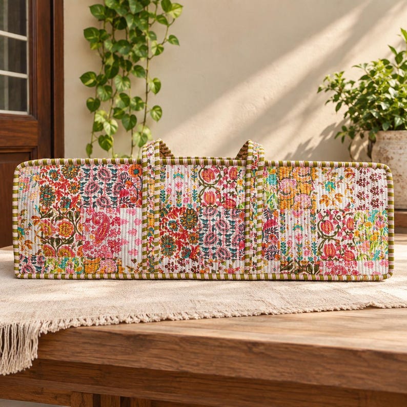 May include: A rectangular quilted tote bag featuring a vibrant patchwork design with various floral and paisley patterns in shades of pink, orange, green, and white. The bag has two vertical fabric handles and a green and white striped trim.