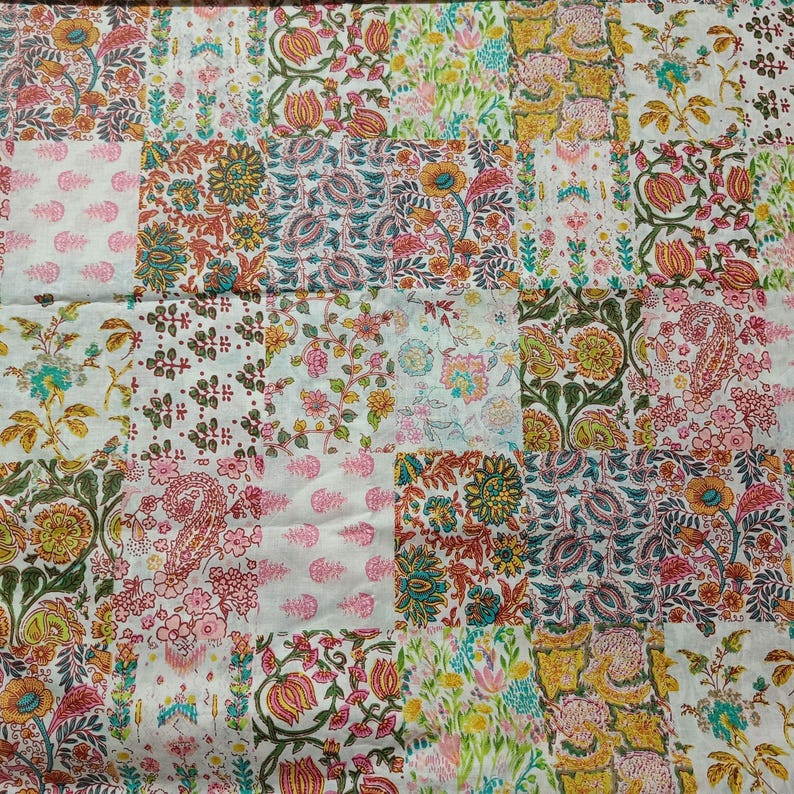May include: A patchwork quilt featuring a grid of square fabric panels with diverse floral and paisley block-print patterns in shades of pink, orange, green, yellow, and blue on a white background, creating a multi-colored textile design.