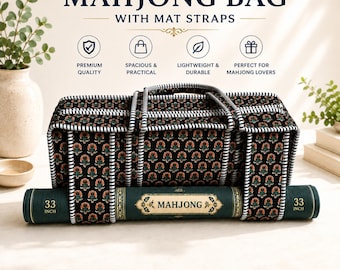 May include: A black rectangular mahjong bag with a repeating floral pattern in orange and green, featuring white and black striped trim and handles. A dark green rolled mahjong mat is secured underneath with straps, labeled 33 INCH on both ends.