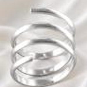 Può includere: Un anello color argento caratterizzato da un design a spirale a più livelli. La fascia è composta da tre bobine continue e sovrapposte che si avvolgono a formare una forma circolare, con una superficie metallica liscia, lucida e riflettente.