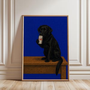 May include: A framed wall art print featuring a black Labrador retriever sitting on a brown wooden table against a solid blue background. The dog is holding a silver soda can with the text Diet Coke printed in red and white on the front label.