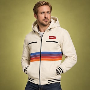 May include: A cream-colored hooded jacket featuring a full-length black zipper, two chest pockets with black trim, and horizontal stripes in blue, purple, and orange across the chest. The text RHM is printed in red on the upper left chest.