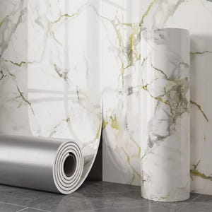 Puede incluir: Un rollo de papel adhesivo con un patrón de mármol blanco y vetas grises y doradas. El material tiene un acabado brillante, mostrando una sección parcialmente desenrollada que exhibe el diseño de mármol y un reverso metálico plateado.