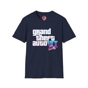 Peut inclure: Un t-shirt bleu marine à manches courtes arborant le texte blanc "grand theft auto" avec le chiffre romain "VI" en dégradé violet et rose, accompagné du mot "Six" en police cursive rose néon centré sur la poitrine.