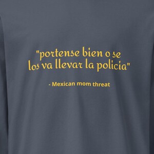 May include: A charcoal gray long-sleeve crewneck shirt featuring yellow text that reads "portense bien o se los va llevar la policia" followed by the text "- Mexican mom threat" centered on the chest area of the garment.