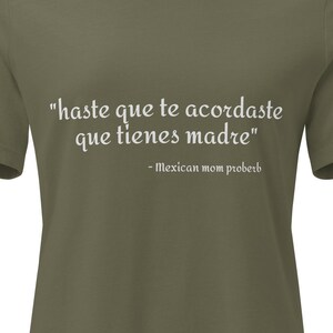 May include: An olive green short-sleeved t-shirt featuring white text that reads "haste que te acordaste que tienes madre" followed by "- Mexican mom proberb" printed in a serif font across the center of the chest area.