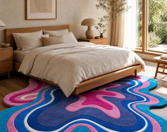 Könnte beinhalten: Ein unregelmäßig geformter Teppich mit einem lebendigen, wellenförmigen Muster aus konzentrischen Schichten in leuchtendem Blau, tiefem Violett, Magenta und Weiß. Der Teppich hat eine dicke, getuftete Textur und liegt auf einem Holzboden.