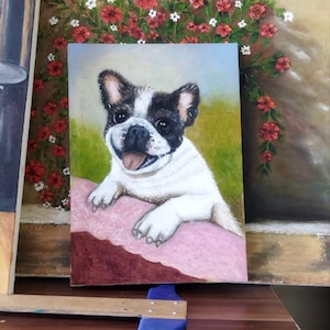 May include: A rectangular oil painting on canvas depicting a black and white French Bulldog puppy with its front paws resting on a pink ledge. The background features a green field and a bush with small red flowers under a light blue sky.