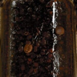 May include: A glass jar filled with dark brown coffee beans. The jar has a silver lid.