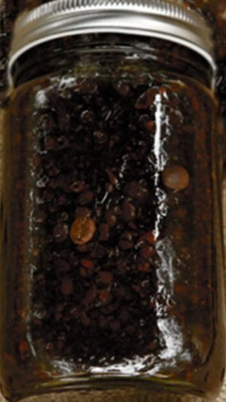 May include: A glass jar filled with dark brown coffee beans. The jar has a silver lid.