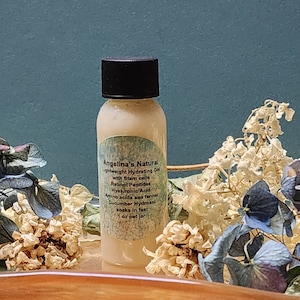 May include: A small, clear plastic bottle with a black lid filled with a light yellow liquid. The bottle has a white label with the text "Angelina's Natural Lightweight Hydrating Gel with Stem cells Retinol Peptides Hyaluronic Acid Amino acids sea fennel Cucumber Hydrosol soaks in fast 1 oz pet jar".