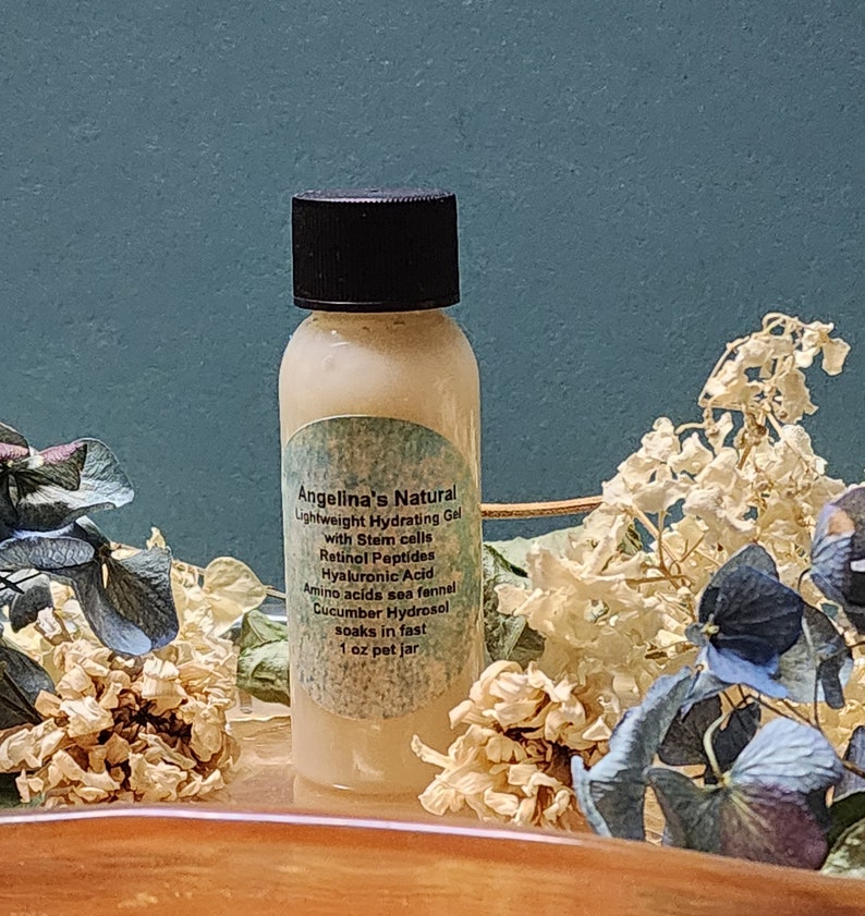 May include: A small, clear plastic bottle with a black lid filled with a light yellow liquid. The bottle has a white label with the text "Angelina's Natural Lightweight Hydrating Gel with Stem cells Retinol Peptides Hyaluronic Acid Amino acids sea fennel Cucumber Hydrosol soaks in fast 1 oz pet jar".