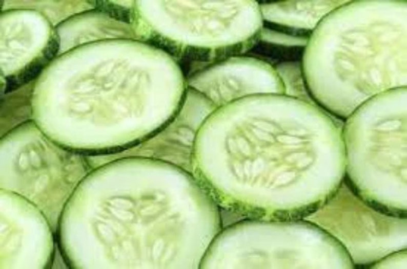 May include: Close-up of thinly sliced green cucumbers. The cucumber slices are arranged in a random pattern, showing the light green flesh and dark green skin.