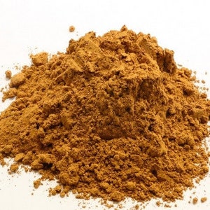 May include: A pile of loose, brown, ground cinnamon powder on a white background.