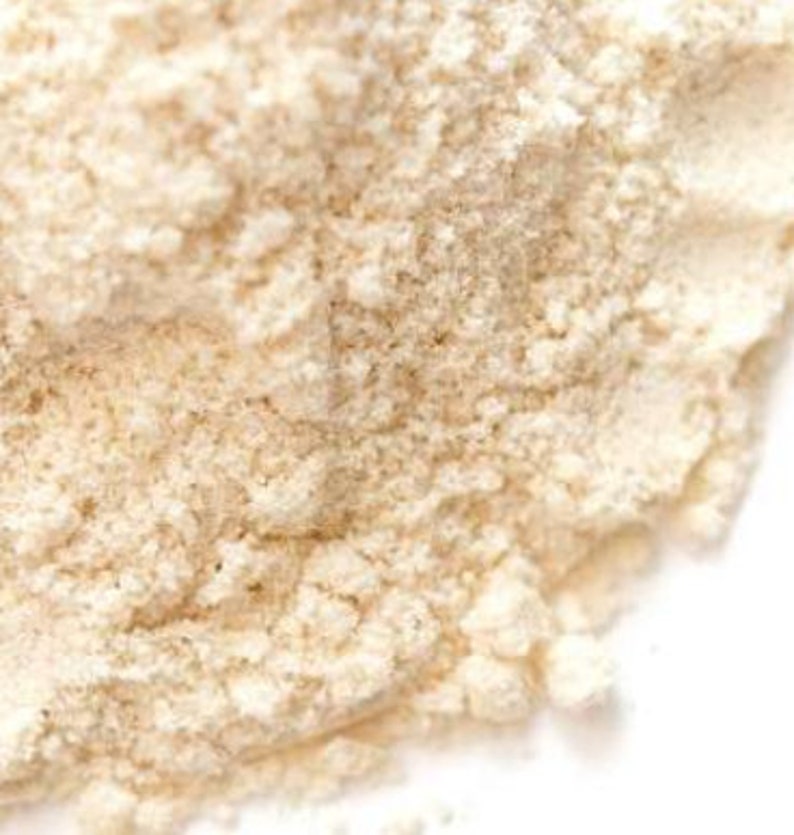 Pu&ograve; includere: Primo piano di un mucchio di polvere beige chiaro con una consistenza granulosa. La polvere sembra essere finemente macinata, con un colore leggermente bianco sporco. L'immagine &egrave; ben illuminata, evidenziando la consistenza e la forma della polvere.