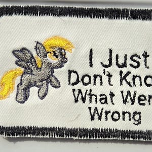 Puede incluir: Un parche rectangular bordado con fondo blanco y borde negro. Presenta un poni gris con crin y cola amarillas, junto al texto bordado en negro: I Just Don't Know What Went Wrong.