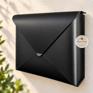 May include: A matte black metal wall-mounted mailbox shaped like a classic envelope with a triangular flap. A circular white sticker on the right side features a maple leaf icon and the text MapleMuse COLLECTIONS, CONNECTING THE WORLD WITH GIFTS.