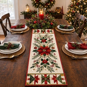 May include: A rectangular fabric table runner featuring a cream-colored center with a printed design of red poinsettias, green pine branches, and red berries. The runner has a red border and ends with a geometric quilt-style pattern in red and green.
