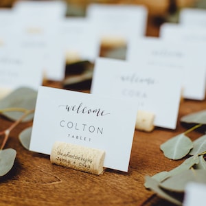 La aventura comienza el titular de la tarjeta de lugar de corcho de vino personalizado o el colocador de lugar, el titular de la tarjeta de nombre de la insignia del nombre del corcho del vino, la boda temática del vino