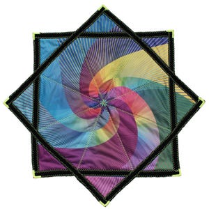 Puede incluir: Una colcha de tela cuadrada con un vibrante patrón de espiral en colores arcoíris que irradia desde el centro. La colcha está bordeada por un grueso borde negro con costura en zigzag y detalles en amarillo neón en las esquinas.