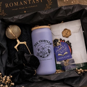 May include: A gift box containing a frosted lavender glass tumbler with a bamboo lid and a black graphic of a dragon, a gold metal tea infuser, a black velvet scrunchie, a wax-sealed envelope, and a purple House of Wind Book Club sticker.