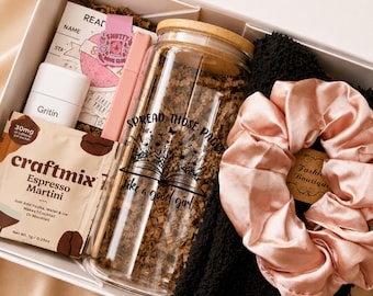 May include: A gift box containing a glass tumbler with a bamboo lid and the text 'SPREAD THOSE PAGES like a good girl', a packet of Craftmix Espresso Martini, a white Gritin box, a pink pen, a reading log, and a pale pink satin scrunchie on a black fabric.