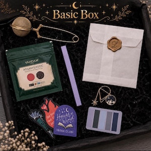 May include: A gift box set containing a gold-tone mesh tea infuser, a green Vahdam Assam Exotic black tea pouch, a lavender pen, a white envelope with a gold wax seal, a gold star and moon charm, three stickers, and a rectangular colour palette card.