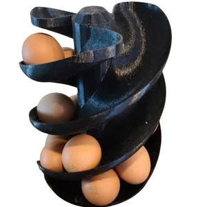 May include: A black spiral egg dispenser rack featuring a central vertical column with a continuous curved track. Multiple brown chicken eggs are positioned along the descending path of the rack, resting in the grooves of the black structure.