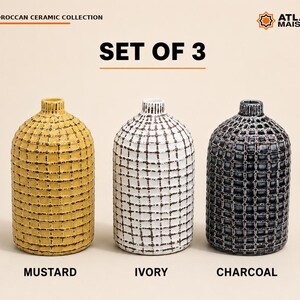 May include: A set of three ceramic vases featuring a textured grid pattern. The vases are coloured mustard, ivory, and charcoal. Text on the image reads: MOROCCAN CERAMIC COLLECTION, SET OF 3, ATLAS MAISON, MUSTARD, IVORY, CHARCOAL.