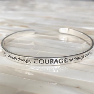 May include: Silver bangle bracelet with the inscription "I cannot change: COURAGE to change the things I can not change."