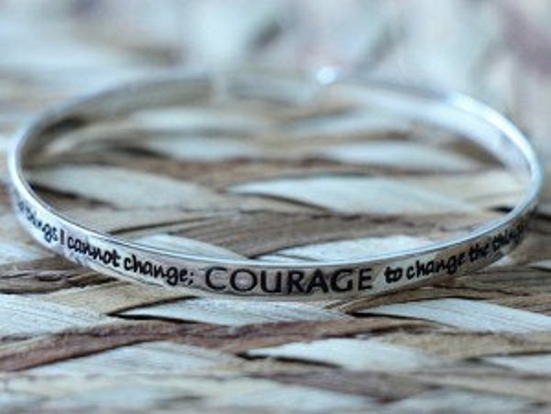 May include: Silver bangle bracelet with the inscription "The things I cannot change; COURAGE to change the things I can."