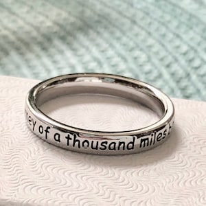 May include: A silver ring with the inscription "journey of a thousand miles"