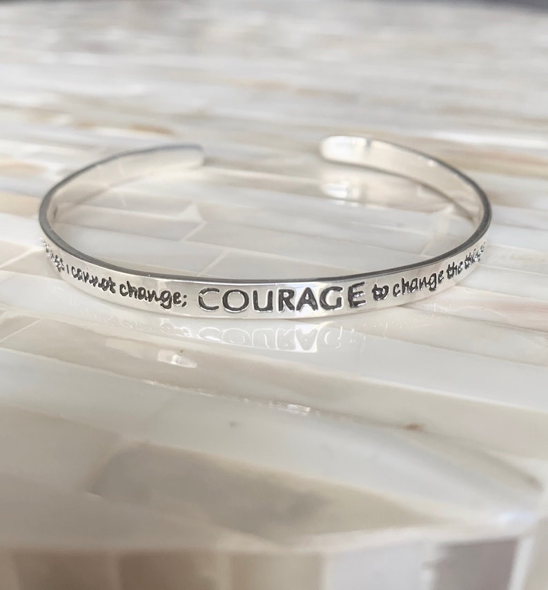 May include: Silver bangle bracelet with the inscription "I cannot change: COURAGE to change the things I can not change."