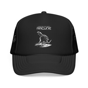 May include: A black trucker hat featuring a white graphic print of a raccoon wearing a cape and holding a small sword. Above the raccoon, the text reads JIMOTHEE CHALAMET and RACUNC in a stylized white font. The hat has a mesh back panel.