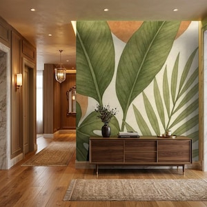 May include: A rectangular wooden sideboard with a smooth finish stands against a wall featuring a large-scale mural of oversized green tropical leaves and soft orange circular shapes on a cream background, with a small vase and books on top.