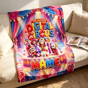 May include: A plush throw blanket featuring a colorful circus-themed graphic with the text THE AMAZING DIGITAL CIRCUS and a customizable NAME section. The design includes cartoon characters on a stage, surrounded by candy, hearts, and curtains.