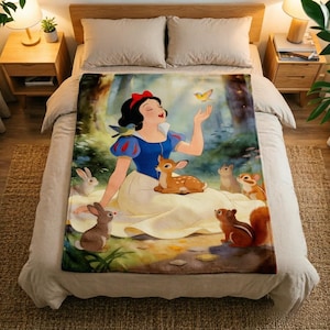 May include: A rectangular fleece blanket featuring a colourful illustration of Snow White wearing a blue and yellow dress, surrounded by forest animals including a deer, rabbits, a squirrel, and birds in a woodland setting with soft lighting.