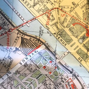 May include: A vintage map of Paris, France, showing the Seine River, the Eiffel Tower, and the Champs-Elysees. The map is printed on a yellowed paper with red and black lines.