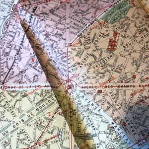 May include: A vintage map of Paris, France, with red and black lines highlighting the streets and avenues. The map is folded in the center, showing the areas around the Champs-&Eacute;lys&eacute;es, the Arc de Triomphe, and the Bois de Boulogne.
