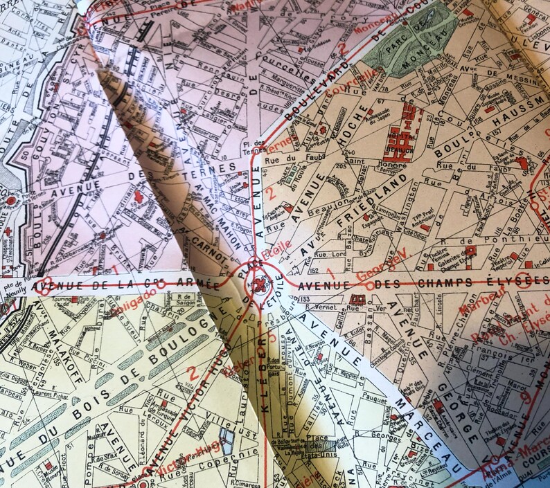 May include: A vintage map of Paris, France, with red and black lines highlighting the streets and avenues. The map is folded in the center, showing the areas around the Champs-&Eacute;lys&eacute;es, the Arc de Triomphe, and the Bois de Boulogne.