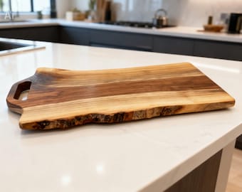 May include: A rectangular wooden serving board featuring a natural live edge on one side and a smooth finish on the other. The board displays varied brown wood grain patterns and includes a cutout handle on the left side for easy gripping.
