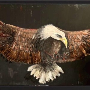 以下が含まれることがあります： 翼を広げて飛ぶハクトウワシの額入り絵画。ワシは白い頭部、黄色い嘴、質感のある筆致で描かれた茶色の羽毛が特徴です。背景は無地の暗い黒色で、強いコントラストを生み出しています。