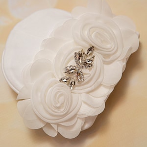 May include: White fabric headband with a large white flower and a rhinestone embellishment.