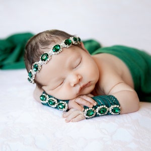 K&ouml;nnte beinhalten: Ein schlafendes Baby, das ein gr&uuml;nes Stirnband mit smaragdgr&uuml;nen Edelsteinen und passende gr&uuml;ne Armb&auml;nder mit smaragdgr&uuml;nen Edelsteinen tr&auml;gt.